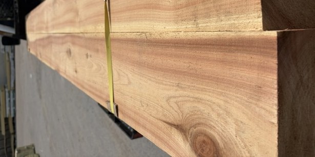 Two long rough-cut cypress beams strapped together, fresh off the mill