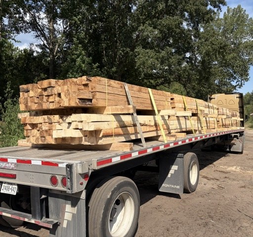 Flatbed 18-wheeler loaded with strapped 4x4 hardwood runners, ready to leave the yard